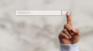 A white tile background with a person's finger pressing the search button on a search engine